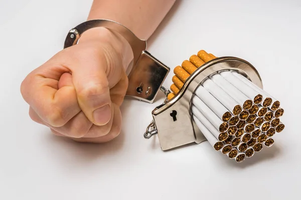 Female hand with handcuffs and cigarettes on white — Stock Photo, Image