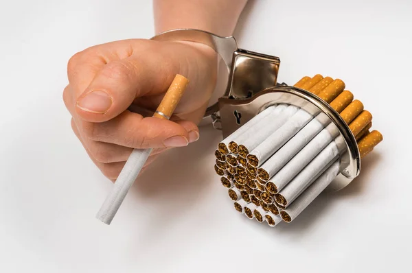 Female hand with handcuffs and cigarettes on white — Stock Photo, Image