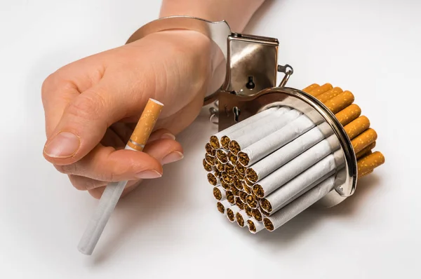 Female hand with handcuffs and cigarettes on white — Stock Photo, Image