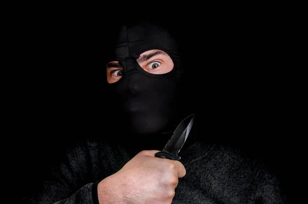 Gemaskerde man in balaclava met mes geïsoleerd op zwart — Stockfoto