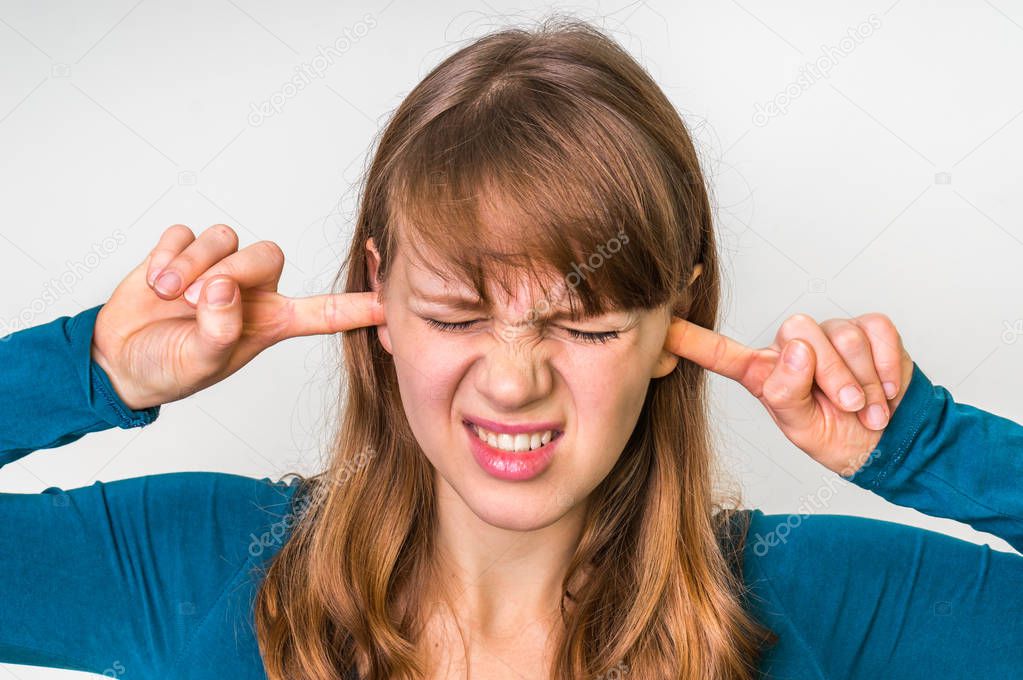 Woman closes ears with fingers to protect from loud noise