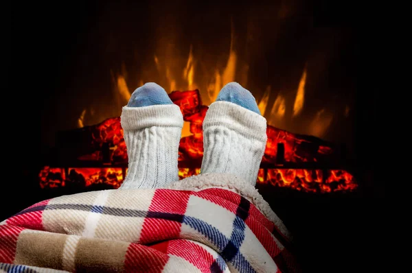 Mujer calentando los pies en calcetines de lana cerca de la chimenea — Foto de Stock