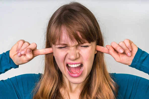 Женщина закрывает уши пальцами, чтобы защитить от громкого шума — стоковое фото