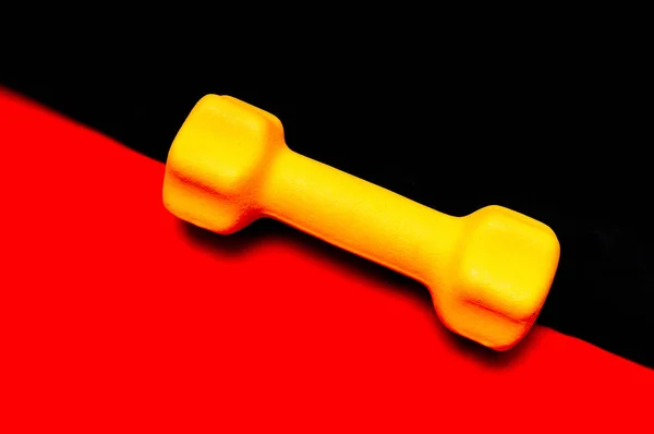 Жовтий гантель для пристосування на червоно-чорному тлі — стокове фото