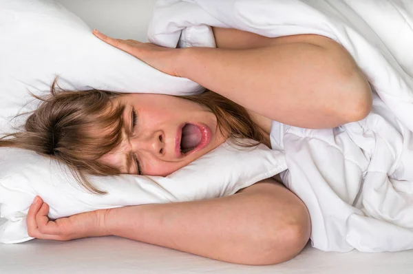 Woman with insomnia covering head and ears with pillow — Stock Photo, Image