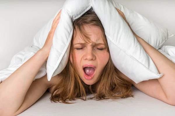 Mujer con insomnio cubriendo cabeza y orejas con almohada — Foto de Stock