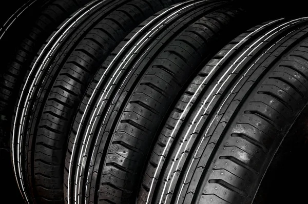 Neumáticos de coches en fila aislados en negro —  Fotos de Stock