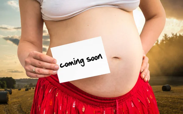Kobieta w ciąży, trzymając papier z napisem: już wkrótce — Zdjęcie stockowe