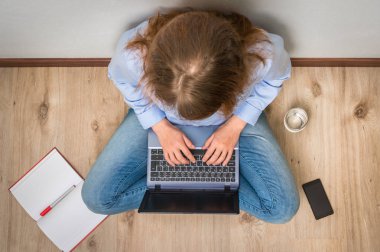 Üstten Görünüm öğrenci dizüstü bilgisayar ile ahşap zemin üzerinde oturuyor