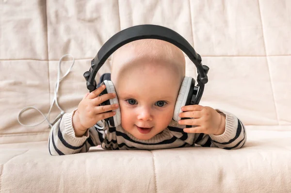 Lindo bebé con auriculares escucha música en casa —  Fotos de Stock