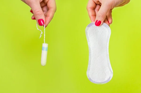 Mulher segurando tampão e guardanapo sanitário nas mãos — Fotografia de Stock