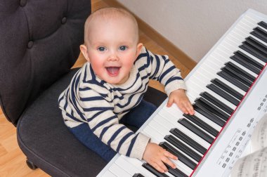 Piyanonun üzerinde oynamaya çalışan şirin bebek