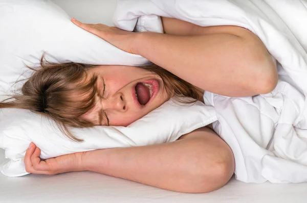 Mulher com a cabeça debaixo da almofada a tentar dormir — Fotografia de Stock