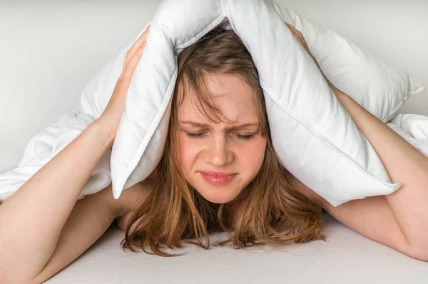 Vrouw met slapeloosheid die betrekking hebben op kop en oren met kussen — Stockfoto