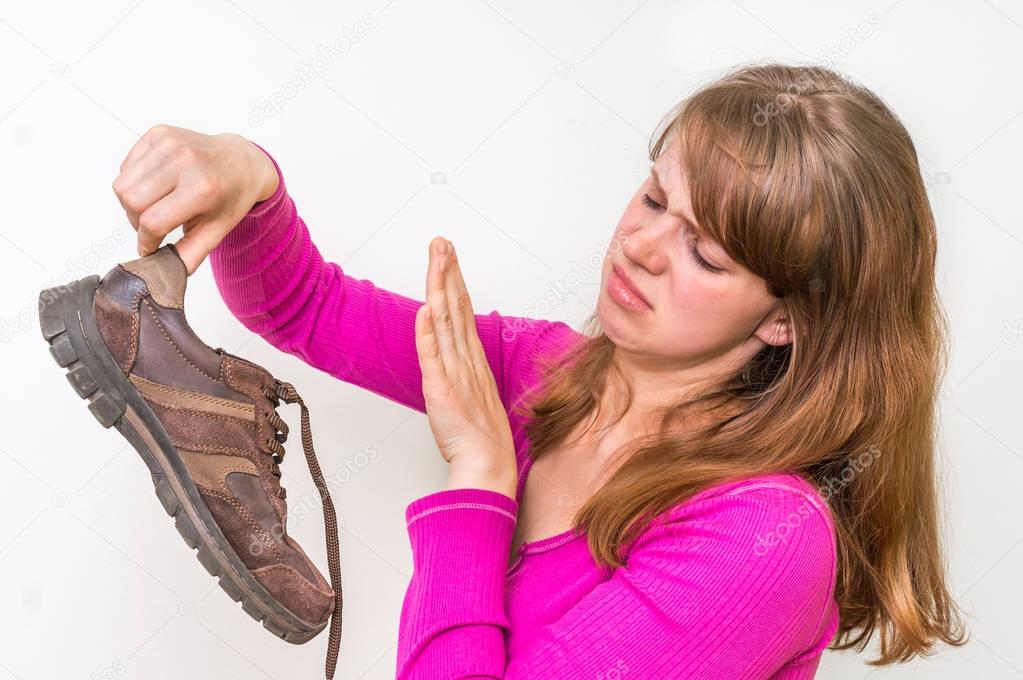 Woman holding dirty stinky shoes