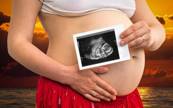 Живот беременной женщины и ультразвуковое сканирование ребенка — стоковое фото