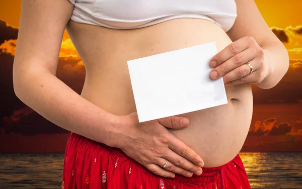 Bauch einer schwangeren Frau mit leerem Papier — Stockfoto