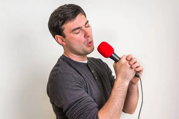 Ung man sjunga med röda mikrofon — Stockfoto