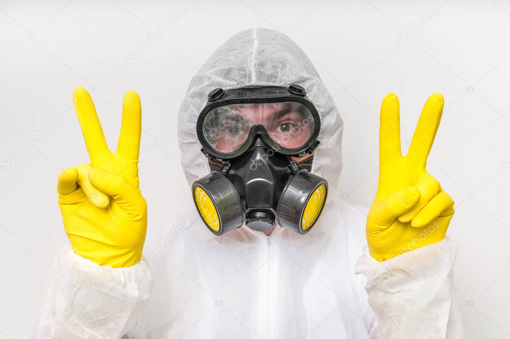Man in coveralls with gas mask is showing victory symbol
