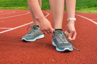 Kadın ayakkabılarını bir stadyumda bağlıyor.