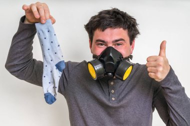 Gaz maskesi ile adam kokmuş çorap tutuyor