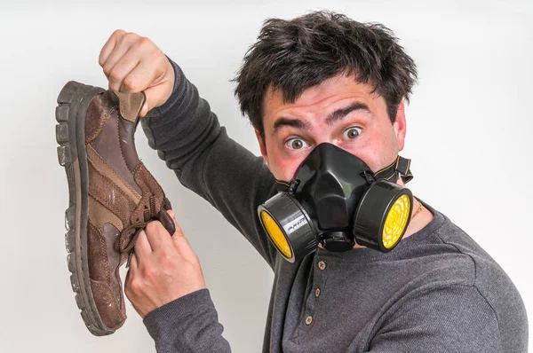 Man med gasmask håller stinkande skor — Stockfoto