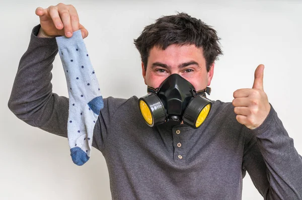 Man med gasmask håller stinkande socka — Stockfoto