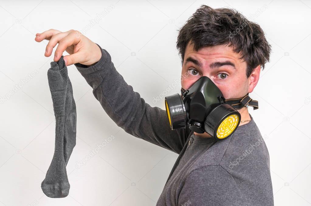 Man with gas mask is holding stinky sock