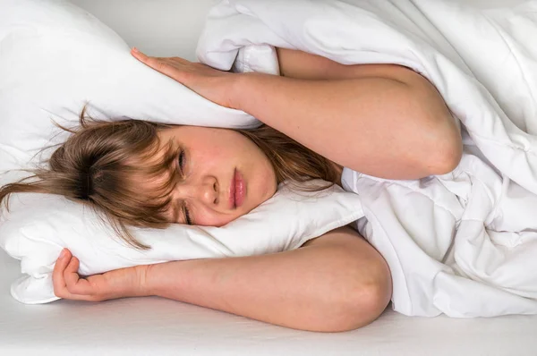 Woman trying to sleep, she covering ears with pillow