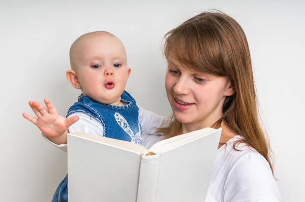 Улыбающаяся мать и ее ребенок читают книгу — стоковое фото