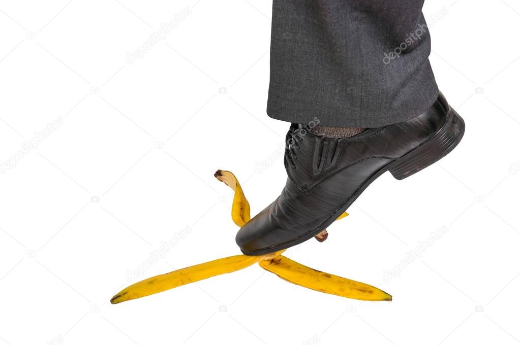 Businessman stepping on banana peel - business risk concept