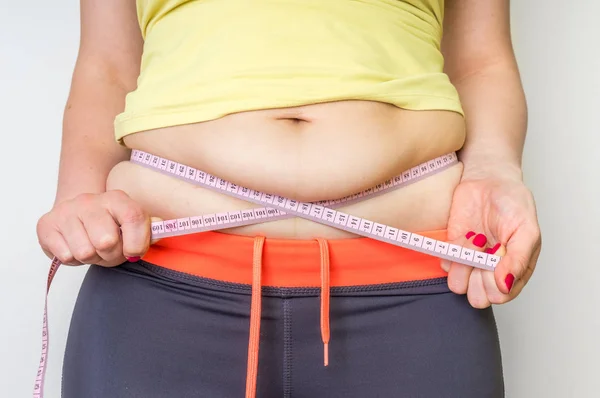 Mujer con sobrepeso con cinta está midiendo la grasa en el vientre — Foto de Stock