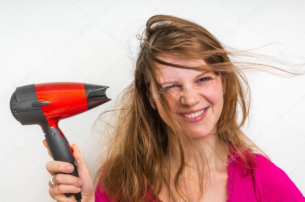Fashion girl with hair dryer dries her hair