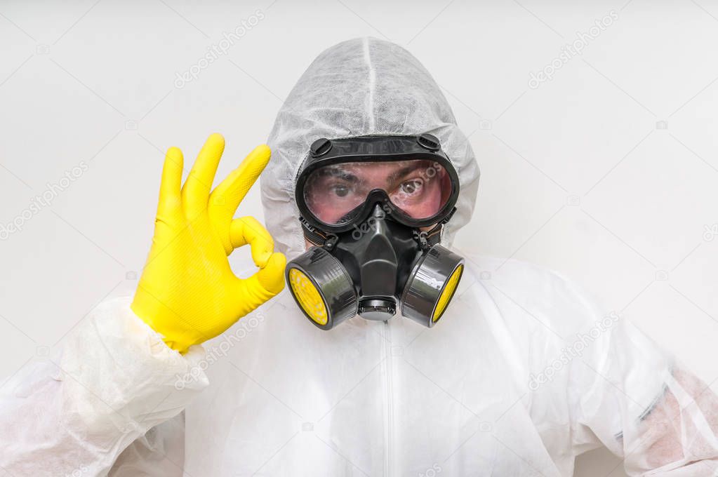 Man in coveralls with gas mask is showing O.K. symbol