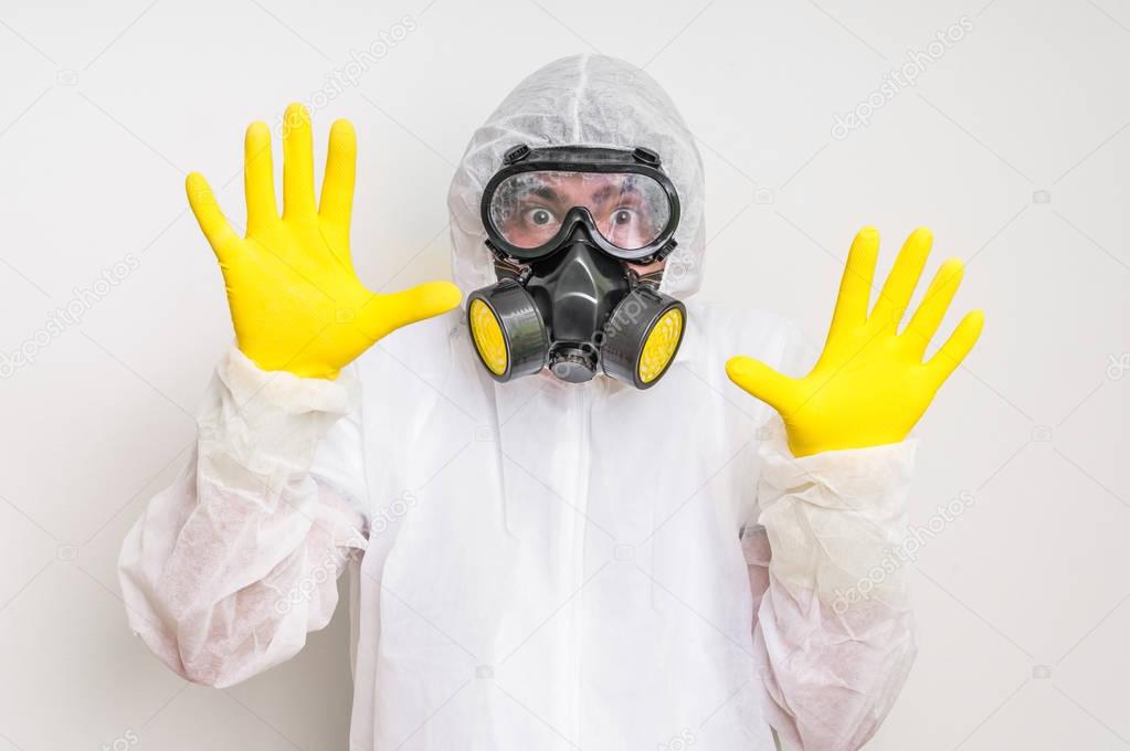 Man in coveralls with gas mask is showing stop gesture