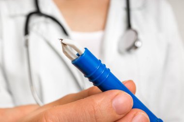 Kadın doktor bir kene cımbızla tutuyor