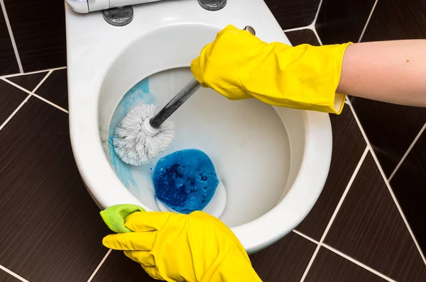 Woman is cleaning toilet bowl using brush — Stock Photo, Image