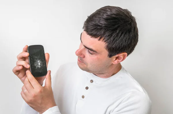 Homem triste está segurando smartphone com tela quebrada — Fotografia de Stock