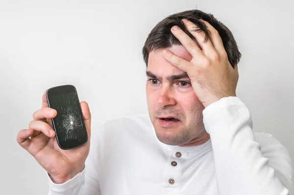 Hombre triste está sosteniendo el teléfono móvil con la pantalla rota — Foto de Stock