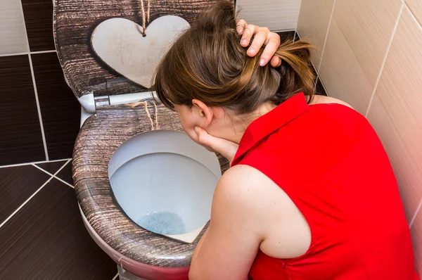 Woman vomiting into the toilet bowl in bathroom — Stock Photo, Image