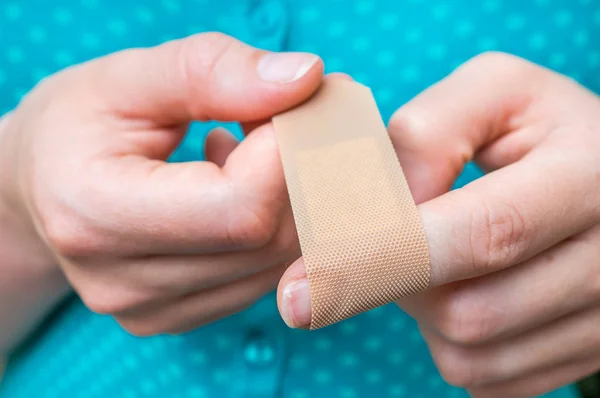 Woman puts a plaster on her injured finger — Stock Photo, Image