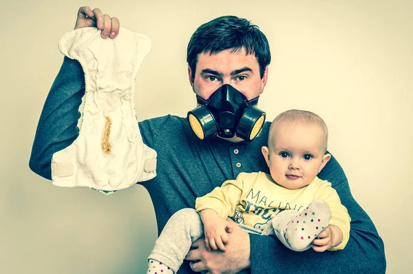 Apa és gázálarc tart a piszkos pelenka és a kisbaba — Stock Fotó