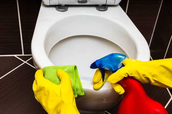 Woman is cleaning toilet bowl with a rag and disinfectant — Stock Photo, Image