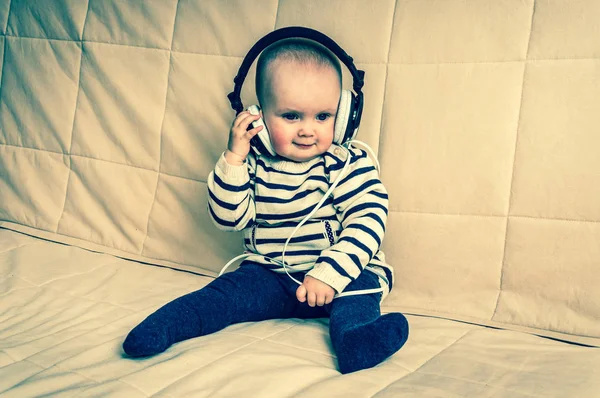 Lindo bebé con auriculares escucha música en casa —  Fotos de Stock