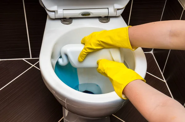 Женщина чистит унитаз моющим средством — стоковое фото