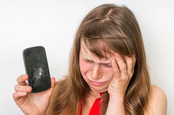 Mujer triste está sosteniendo el teléfono móvil con la pantalla rota — Foto de Stock