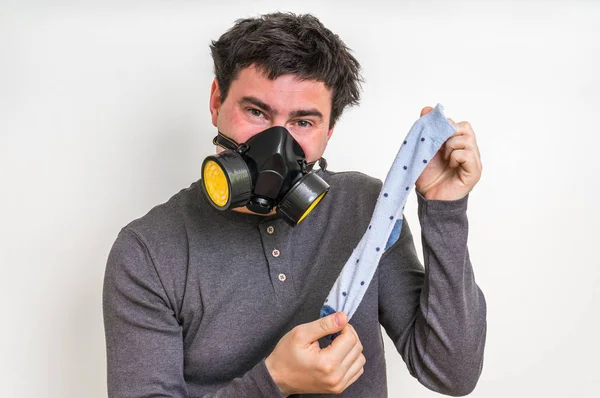 Man med gasmask håller stinkande socka — Stockfoto