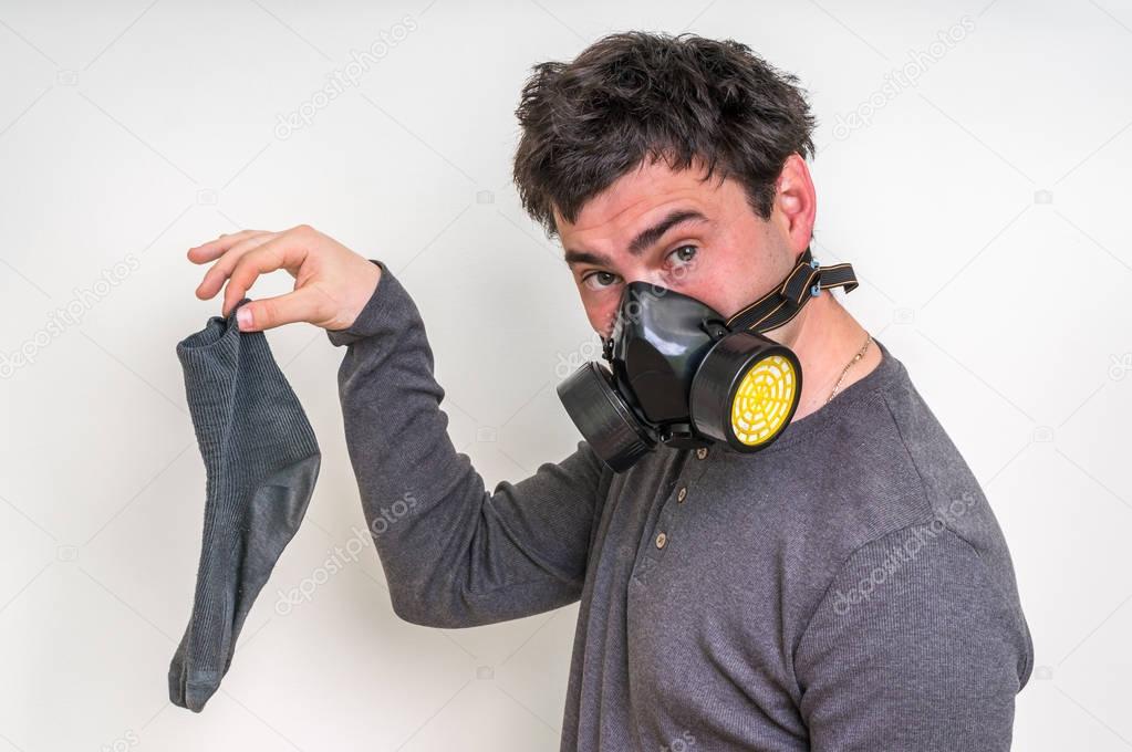 Man with gas mask is holding dirty stinky sock