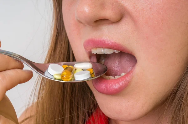 Mujer joven comiendo pastillas en una cuchara — Foto de Stock