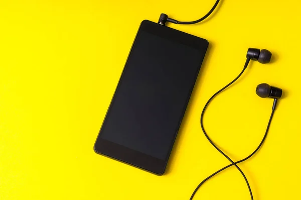 Sarı arka plan üzerinde kulaklık ile cep telefonu — Stok fotoğraf